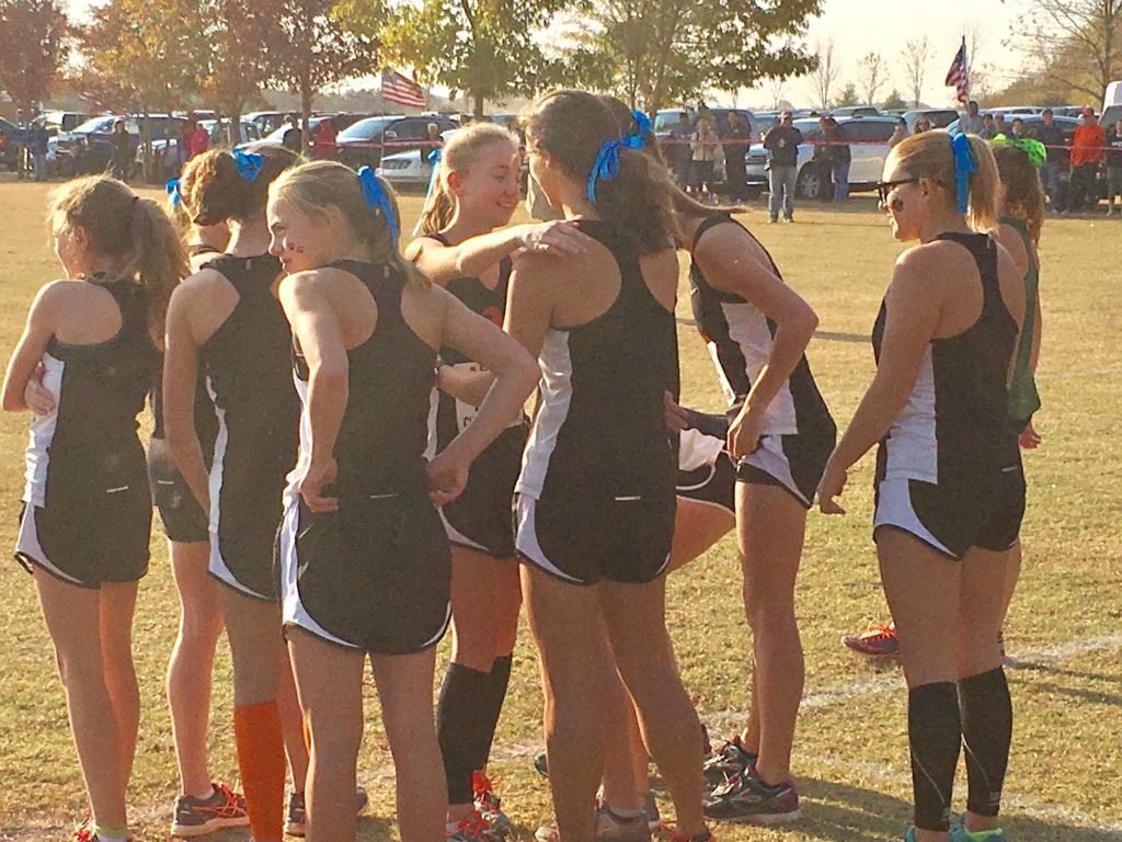 Alexandria's Abby Nunnelly made it a point to embrace each of her teammates before running in the Class 5A race that opened Saturday's AHSAA Cross Country Championships. On the cover, the Pleasant Valley girls team displays their second state championship trophy.