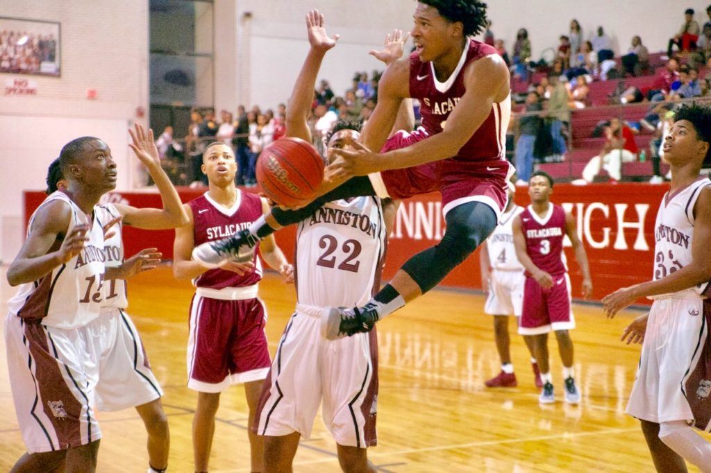 All eyes are on Sylacauga's Malik Canford as he makes an acrobatic move in front of Anniston's Jakoey Bradford (15) and Tareeq Packer-Wood. (Photo by B.J. Franklin/GungHo Photos)