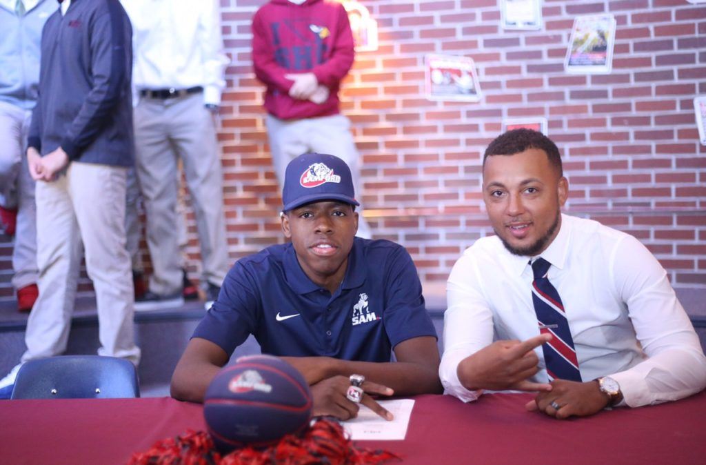 Sacred Heart coach Ralph Graves (R) lets everyone know Kevion Nolan is the school's first-ever Division I sports signee. Below, Nolan is surrounded by the three biggest influences on his success on the court (from left) D.J. Heath, Graves and Diante Wood. (Photos by Kristen Stringer/KrispPics Photography)