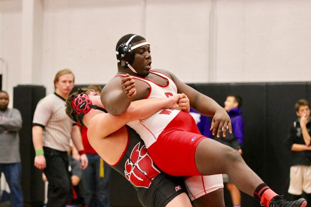 Weaver's Caleb Allison (L) prepares to dump Saks Jordan Brooks in the move that set up his heavyweight win. On the cover, Cleburne County's Dylan Turner displays the most valuable wrestler belt. (Above photo by Daniel Lee) 