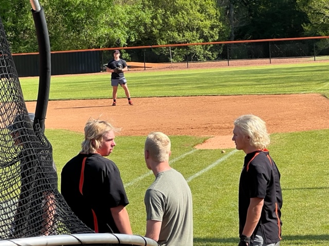 Several Alexandria players wait their turn in the batting cage Thursday having fully embraced the team’s bleached blonde look for the playoffs.