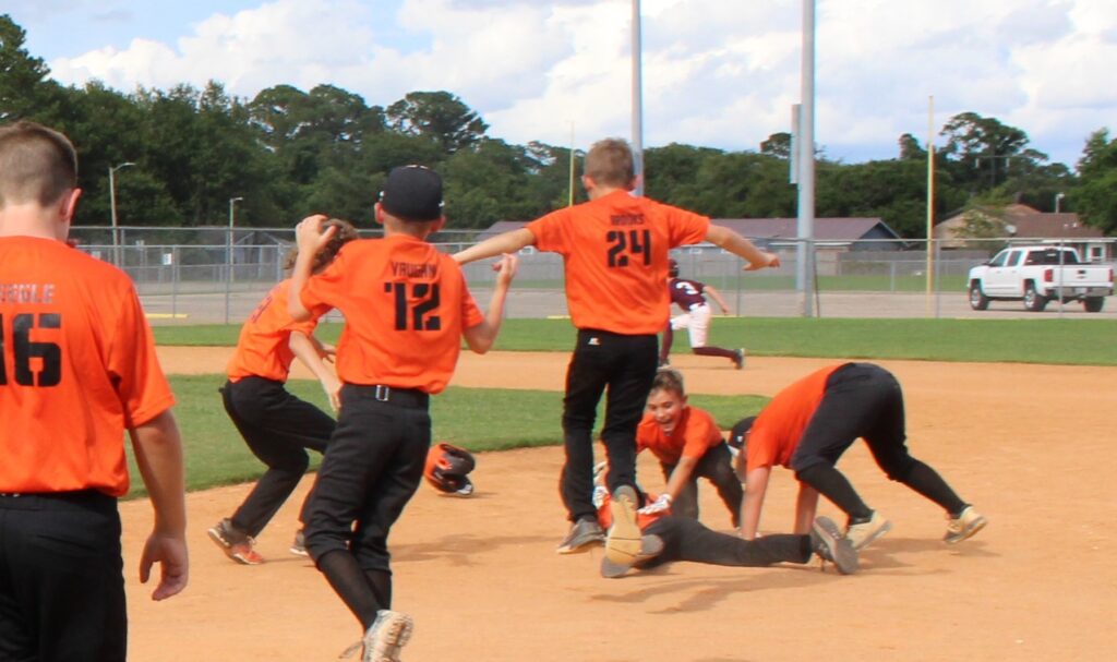 The Alexandria 10U Stars dog pile on J.T. McElroy after his walk-off hit in the USSSA 10U World Series championship game. On the cover, the players and coaches pour our of the dugout to celebrate. (Photos by Leslie Third)