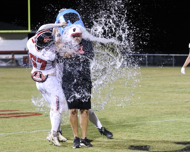 Weaver coach Gary Atchley gets the ice bucket treatment, courtesy of sophomore lineman Brandon Jolliff, to celebrate the Bearcats’ first win of the season. (Photo by Greg Warren)