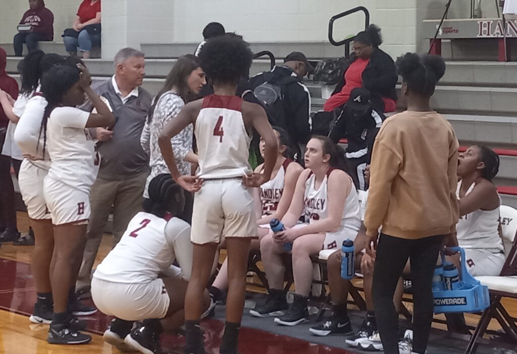 Gracie Williams (center) listens as Handley coach Courtney Screws talks during a timeout during their Class 4A, Area 8 tournament game against Munford on Monday. She scored her first basket of the season in Handley’s 58-15 victory. (Photo by Joe Medley)