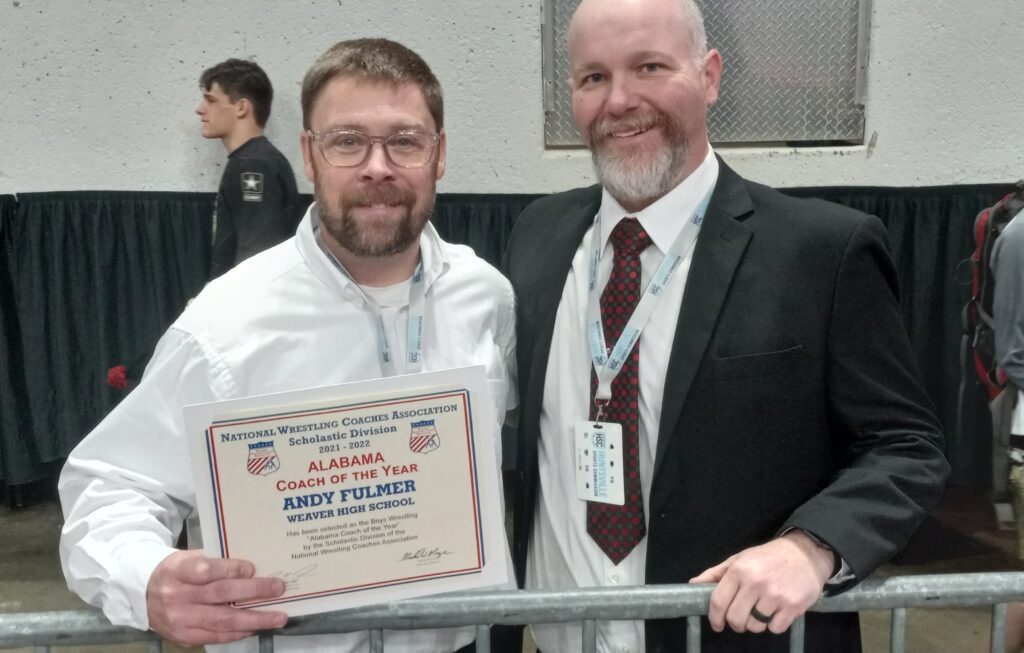 Weaver head coach Andy Fulmer poses with assistant Justin Brown and a certificate showing that coaches voted Fulmer as coach of the year for 2021-22, when Weaver won the first of its now two consecutive state championships. (Photo by Joe Medley)