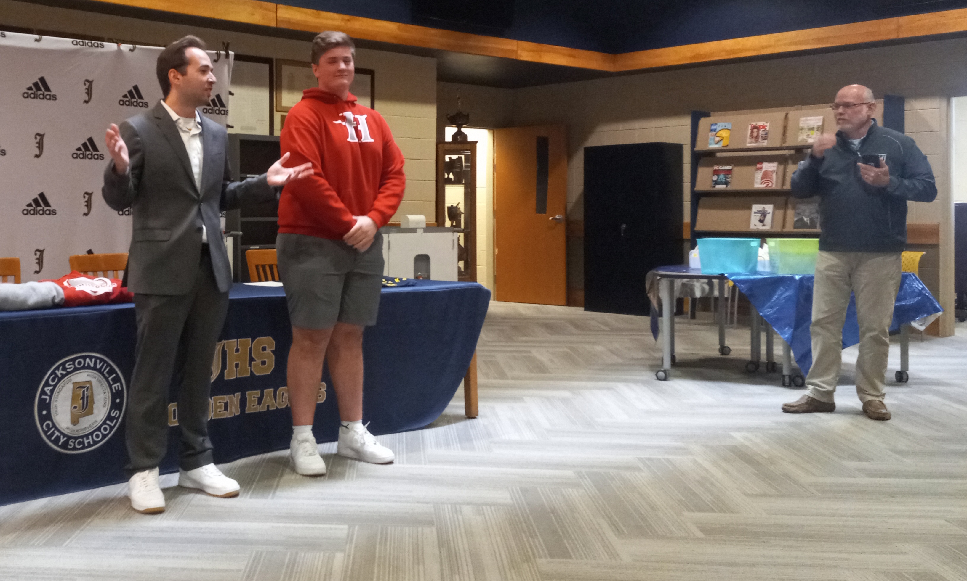 Huntingdon College’s ESports director Justin Ells (left) talks as Jacksonville’s Hayden Smith and Jacksonville principal Russ Waits looks on during Wednesday’s signing ceremony in the school’s library. (Photo by Joe Medley)