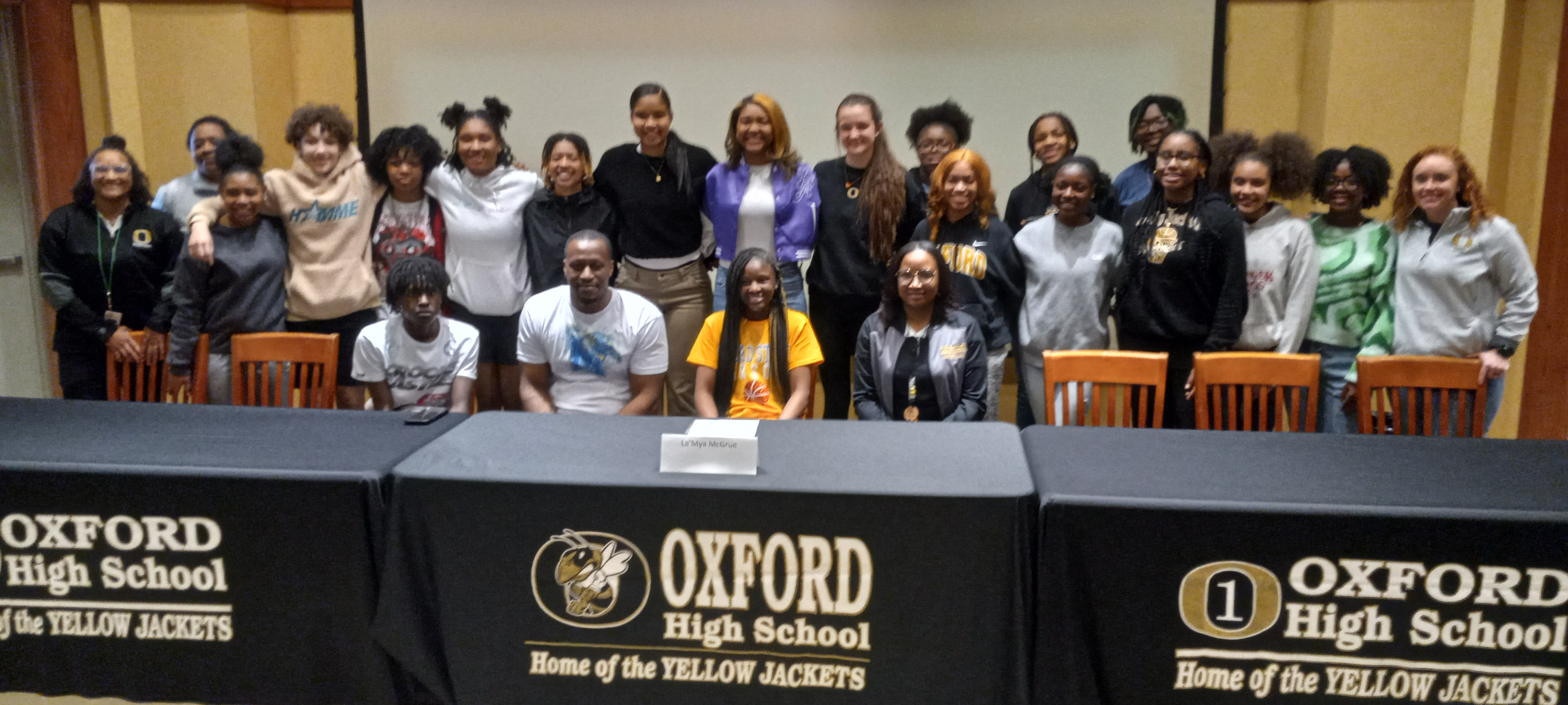 Oxford’s La’Mya McGrue (bottom, center) and family members pose with teammates and coaches at a celebration of her signing to play for Snead State Community College. To her left is her mom, Shavon Wysinger, also an Oxford assistant coach. (Photo by Joe Medley)