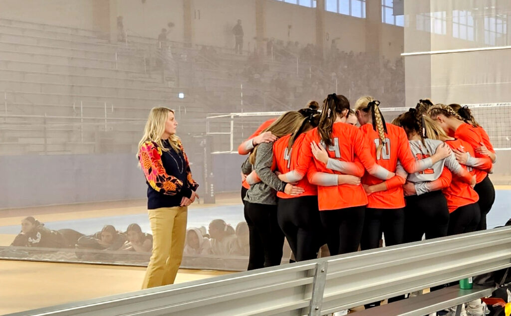 With Pleasant Valley’s team watching behind the net, Alexandria and head coach Whitney Welch huddle before their Class 5A semifinal match with Arab. (Photo by Joe Medley)