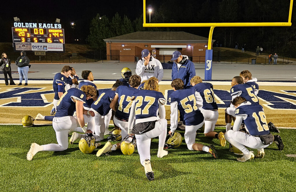 Jacksonville offensive coordinator Jamison Edwards and head coach Clint Smith talk with Golden Eagle seniors Friday, after a loss to Catholic-Montgomery in the Class 4A quarterfinals. (Photo by Joe Medley)