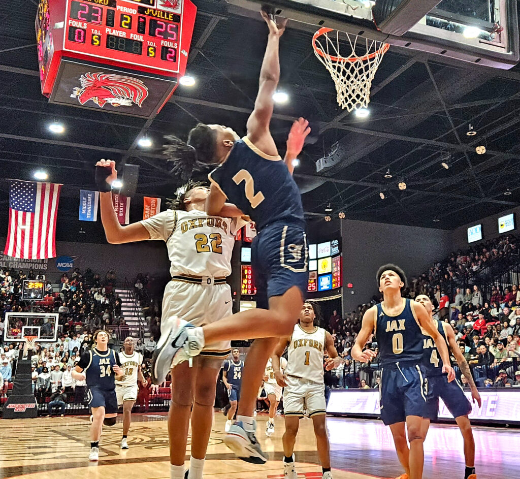 Jacksonville’s Jaquan Ervin goes to the basket for two as Oxfords Marcus Perry, Jr. defends during Friday’s Calhoun County boys’ final in Pete Mathews Coliseum. (Photo by Joe Medley)