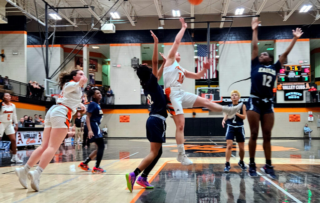 Alexandria’s Charlee Parris drives as Jacksonville’s DeAsia Prothro (12) and Jayci Taylor (32) challenge Thursday at Alexandria. (Photo by Joe Medley)