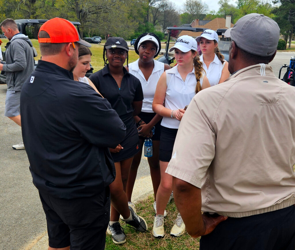 Alexandria coach Craig Kiker talks to the Valley Cubs after Monday’s first round of the Calhoun County tournament at Pine Hill Country Club. Nevaeh Foster (center) shot a team-best 82, and the two-time defending champion Valley Cubs stand six strokes off the lead headed into Tuesday’s final round. (Photo by Joe Medley)