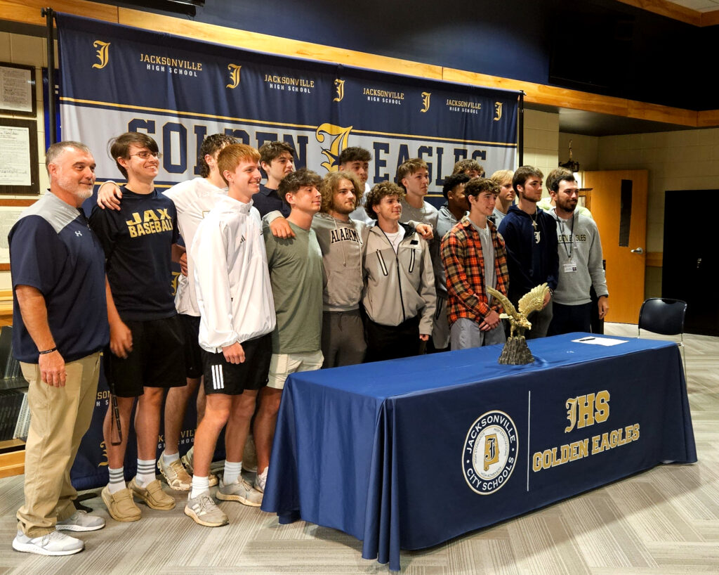 Jacksonville baseball coach Jamison Edwards and players pose for a picture with senior Cole Guthrie during Guthrie’s signing ceremony Thursday. (Photo by Joe Medley)
